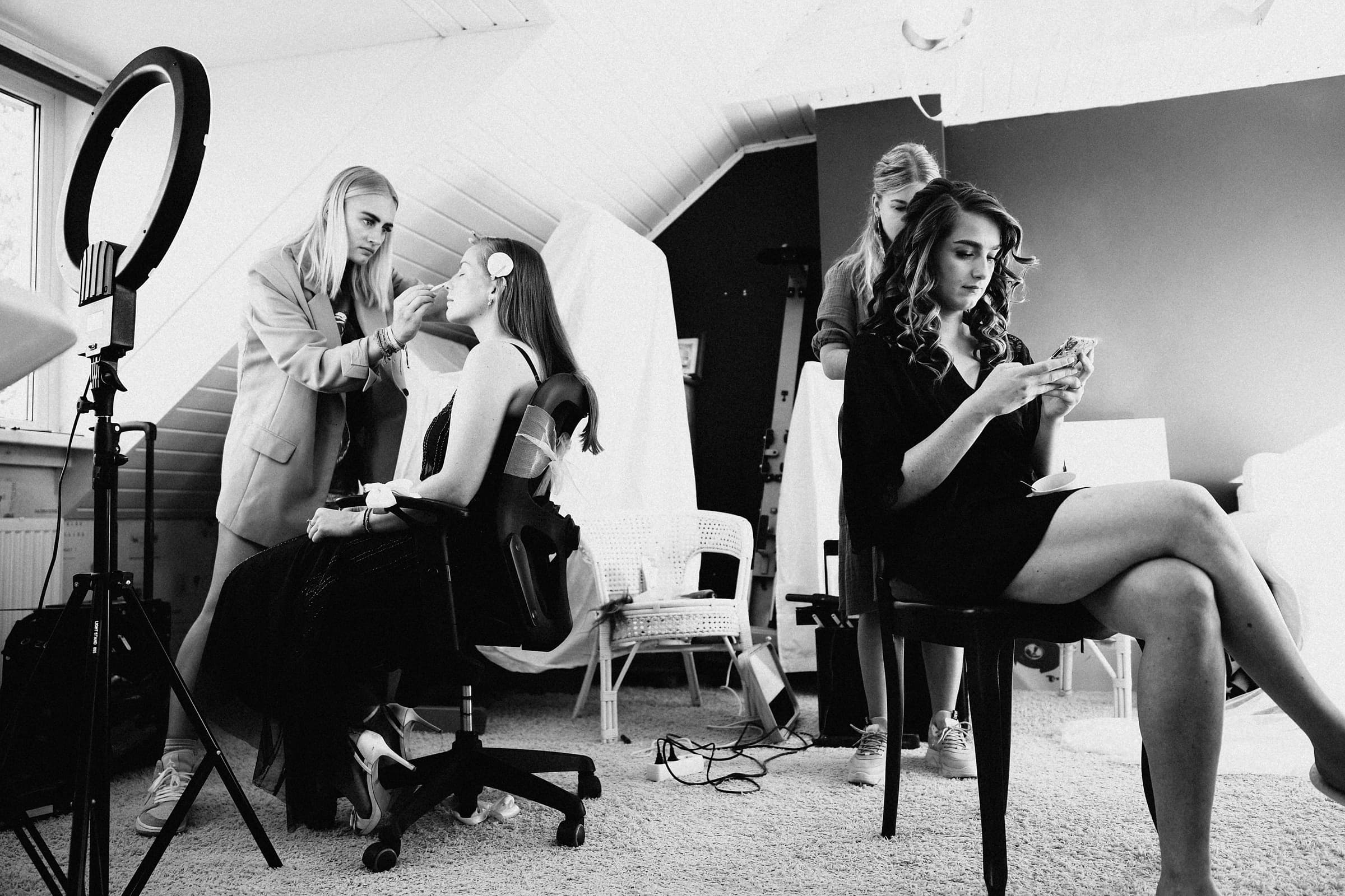 Two stylists doing a bride's hair and makeup during wedding morning preparation