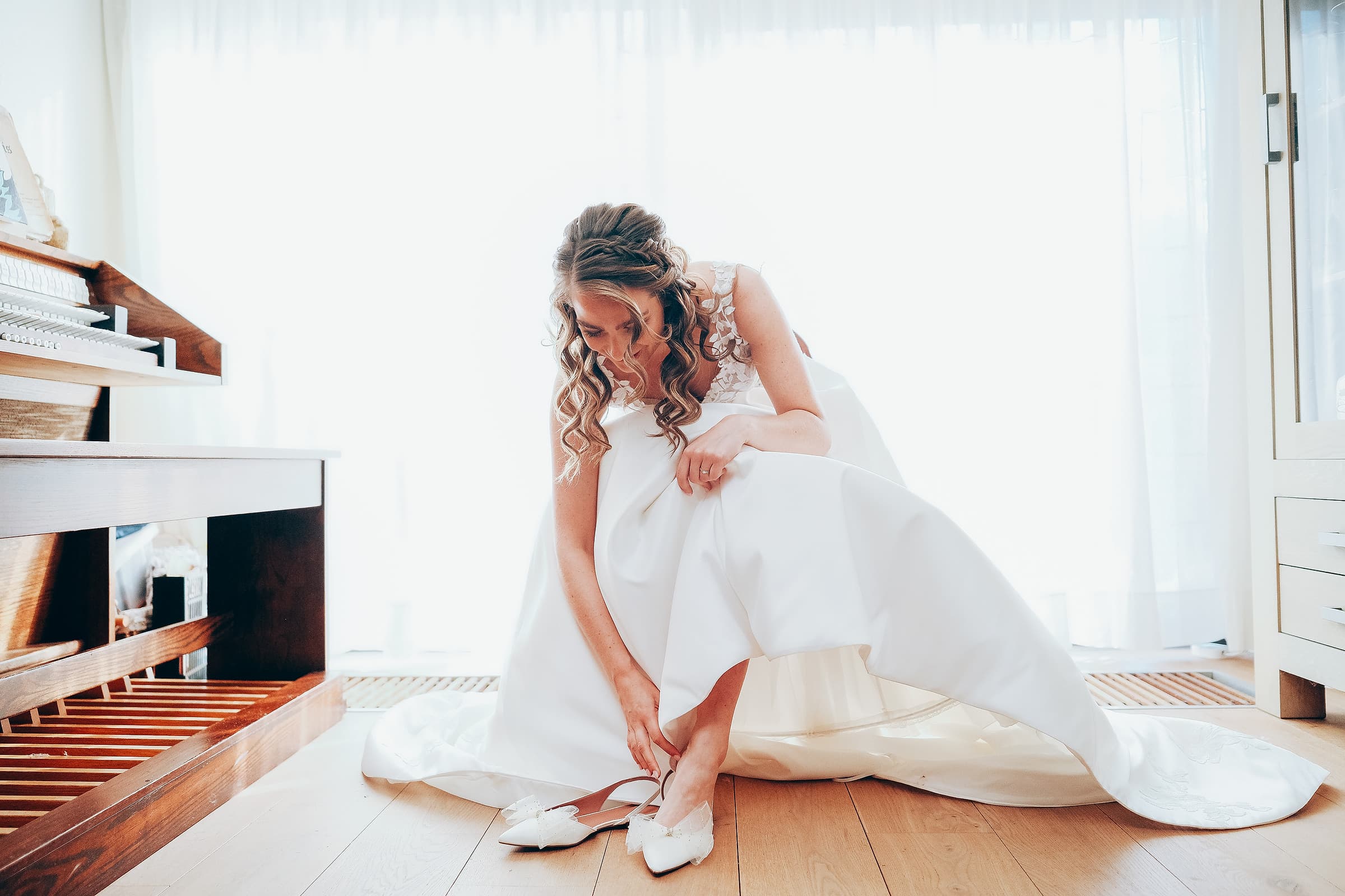 A bride glancing down as she gets ready in soft window light before the ceremony
