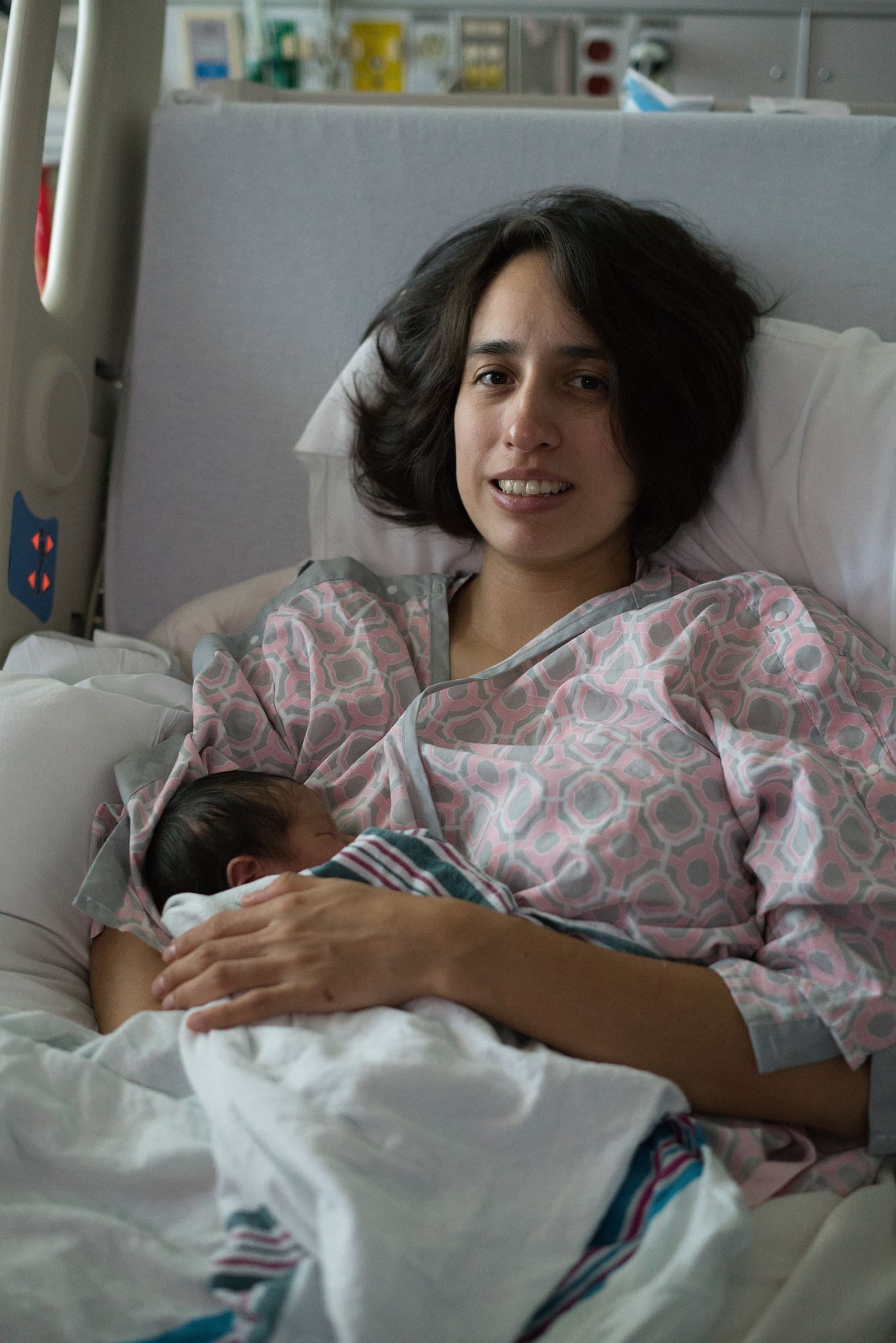 A new mother holding her newborn baby in a hospital bed shortly after giving birth