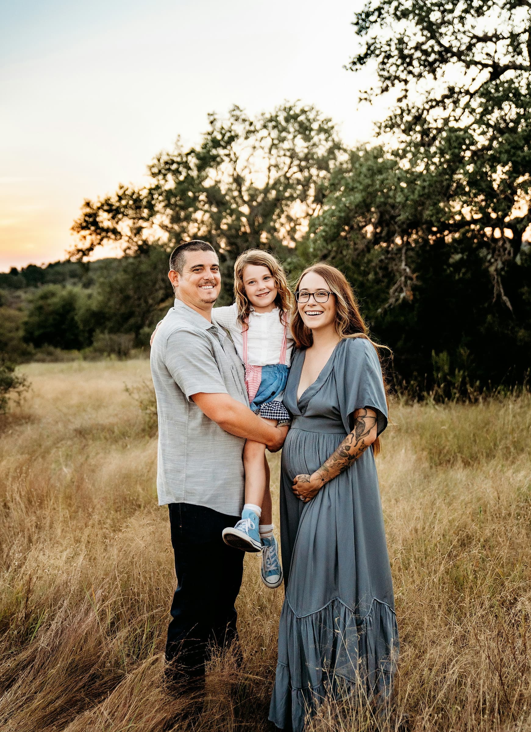 A family standing together in a golden field at sunset during a portrait session