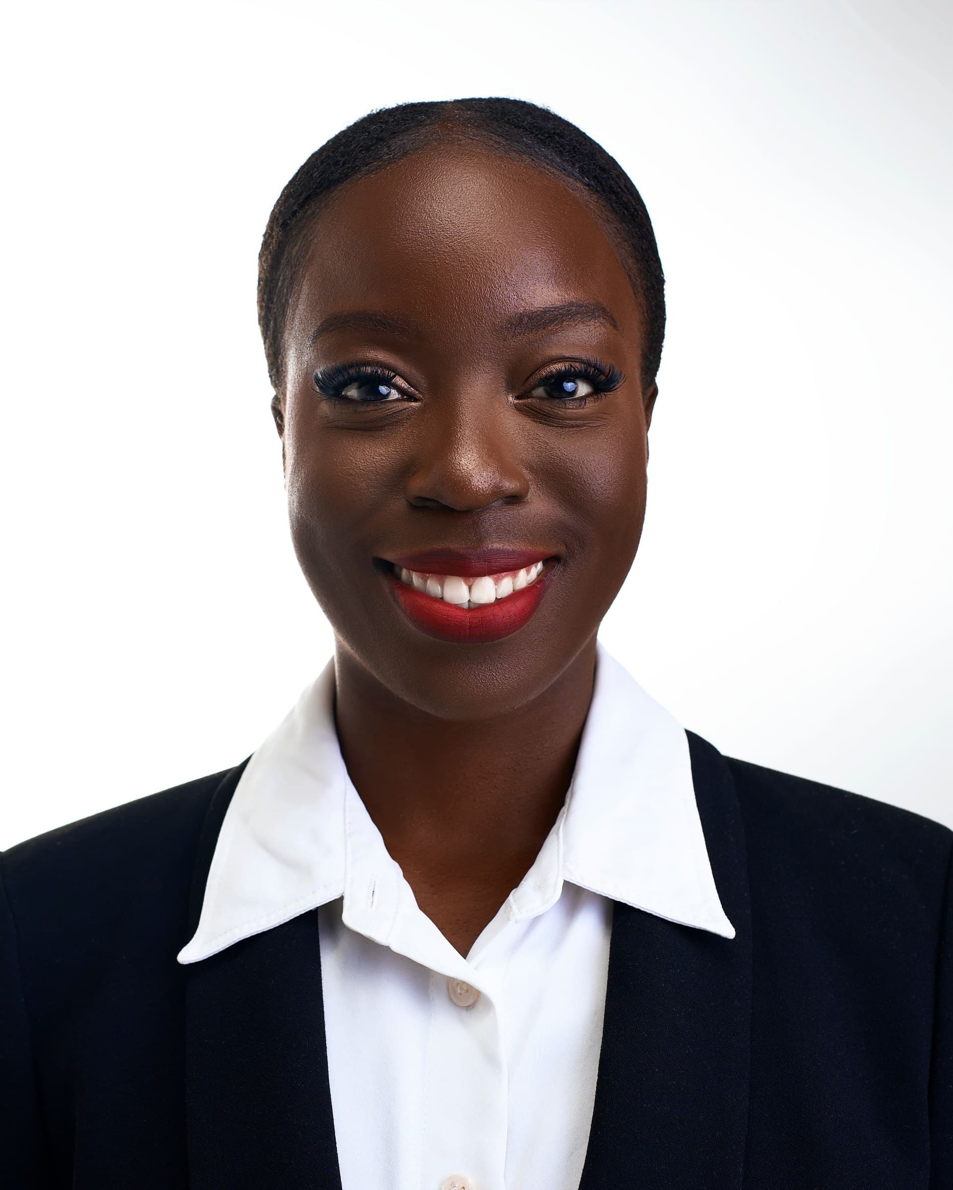 A confident professional in a navy blazer and white shirt photographed against a clean white background for a corporate headshot