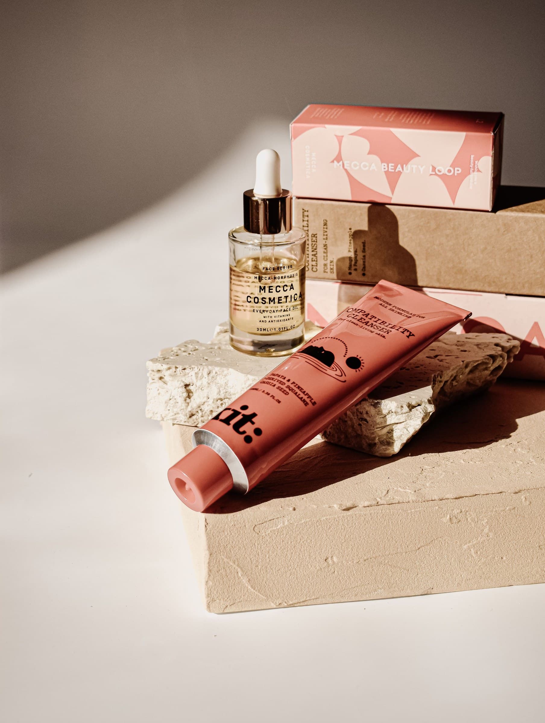 Skincare products styled on stone plinths with packaging boxes and hard directional shadows