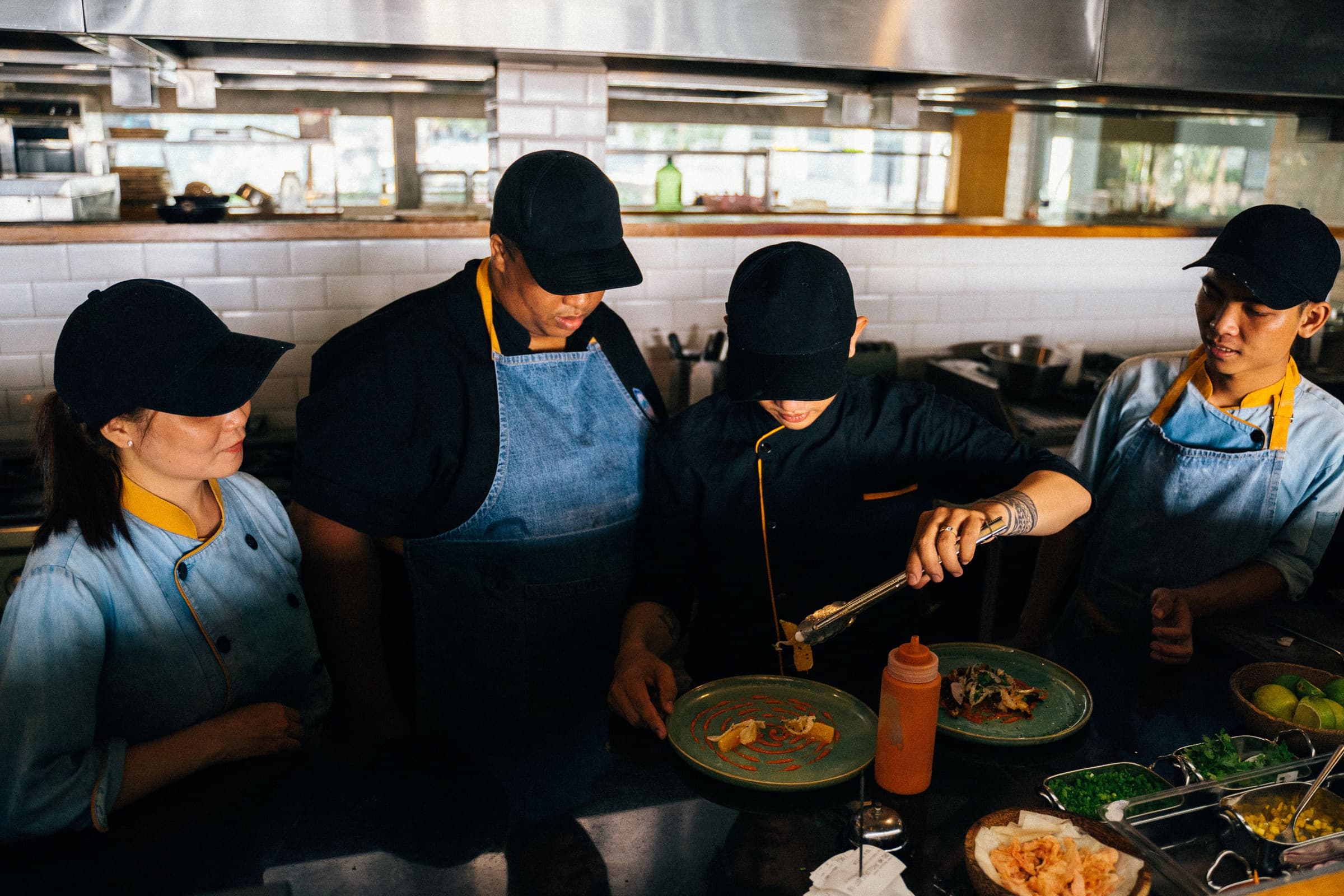 A kitchen team plating dishes together during service in a restaurant