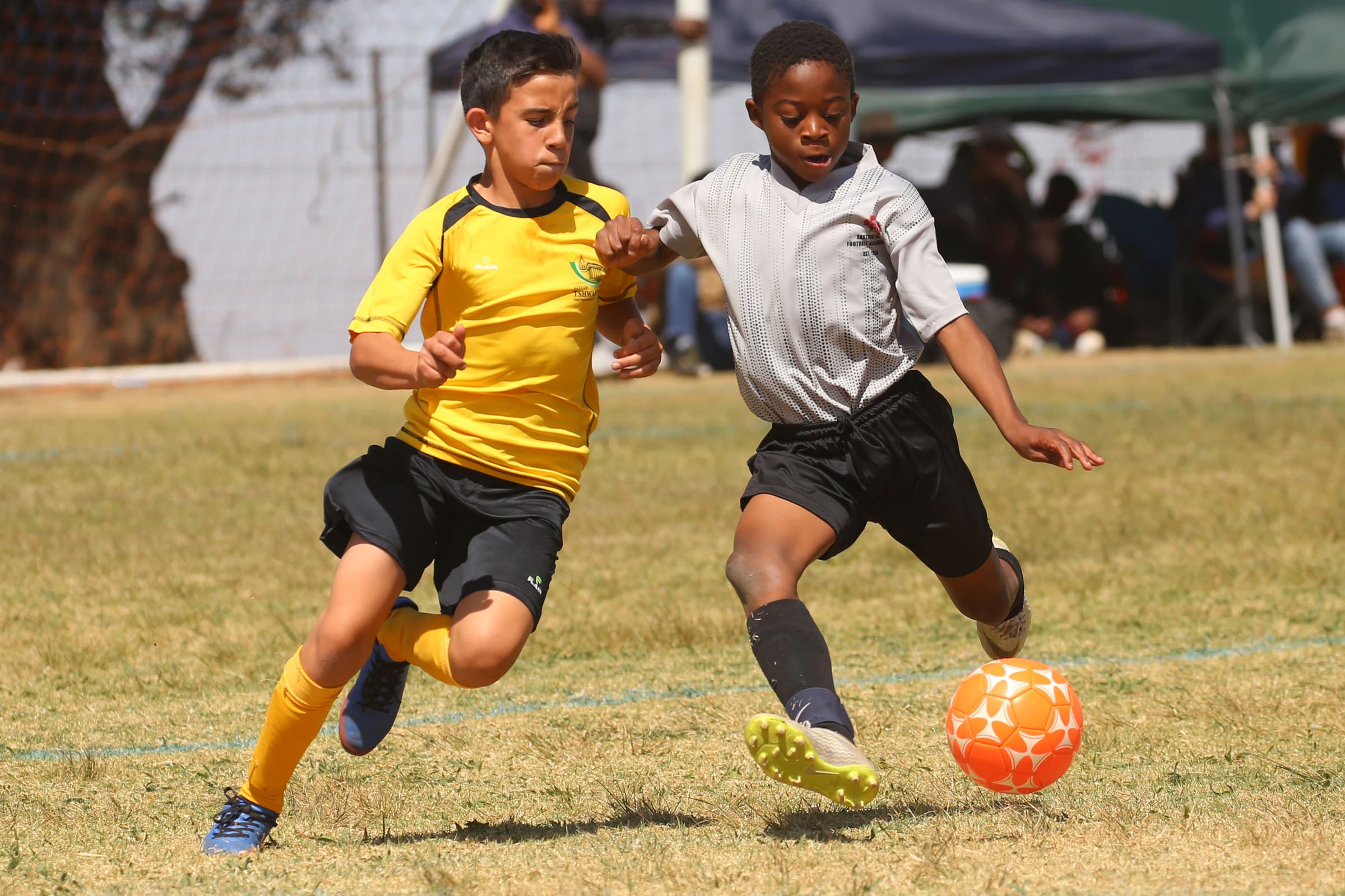 Two young footballers chasing the ball during a youth match on a sunlit pitch