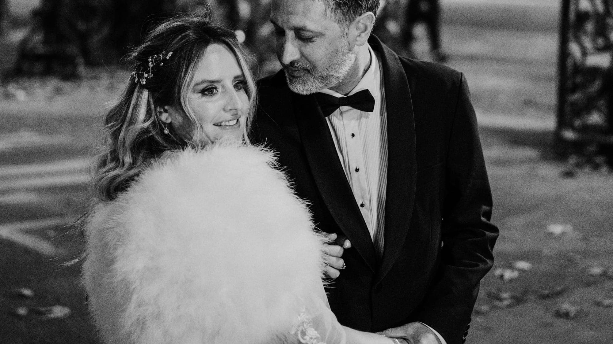 A bride and groom close together on a Paris street at night